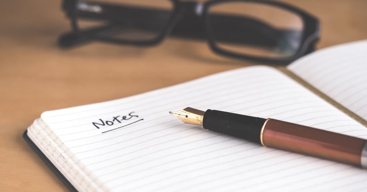 デスクでノートに人生の思い出を書き留めるシニア女性